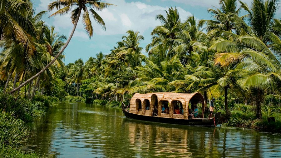 Houseboat gliding along palm-fringed Kerala backwaters